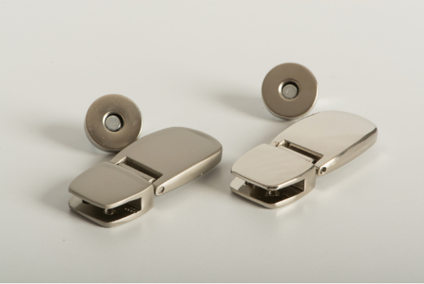 Broche de imán metálico con bisagra de 43 mm de largo y base con tornillos ocultos, en acabado mate, ideal para sujetar solapas o aplicaciones similares. Broche de imán metálico con bisagra de 43 mm de largo y base con tornillos ocultos, en acabado mate, ideal para sujetar solapas o aplicaciones similares.